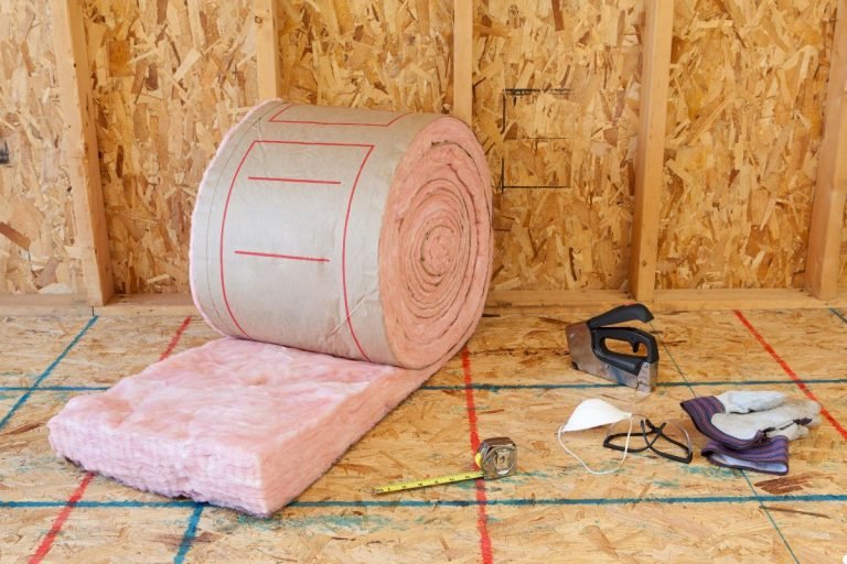 A roll of pink insulation material is placed on the floor, ready for use in construction or home improvement projects.