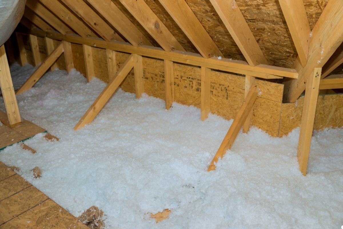 Insulation installed in an attic, featuring wood framing and layers of insulation material for energy efficiency. 
